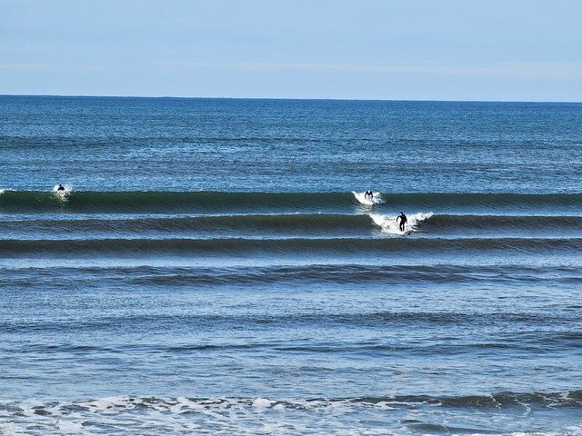 2 surfers catching waves in front of the shop